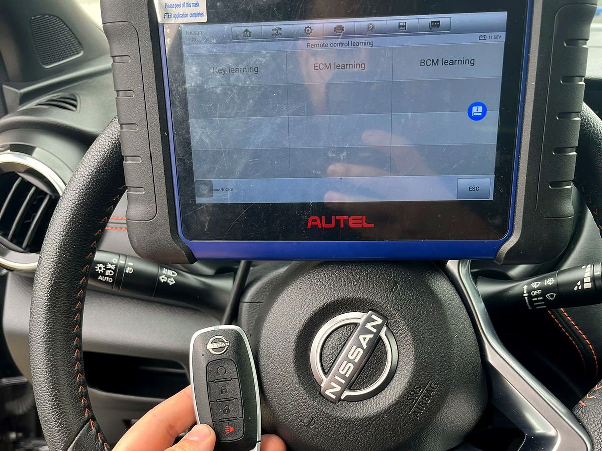 Nissan smart key being programmed to the vehicle with a diagnostic tablet in the driver's seat by a San Diego locksmith