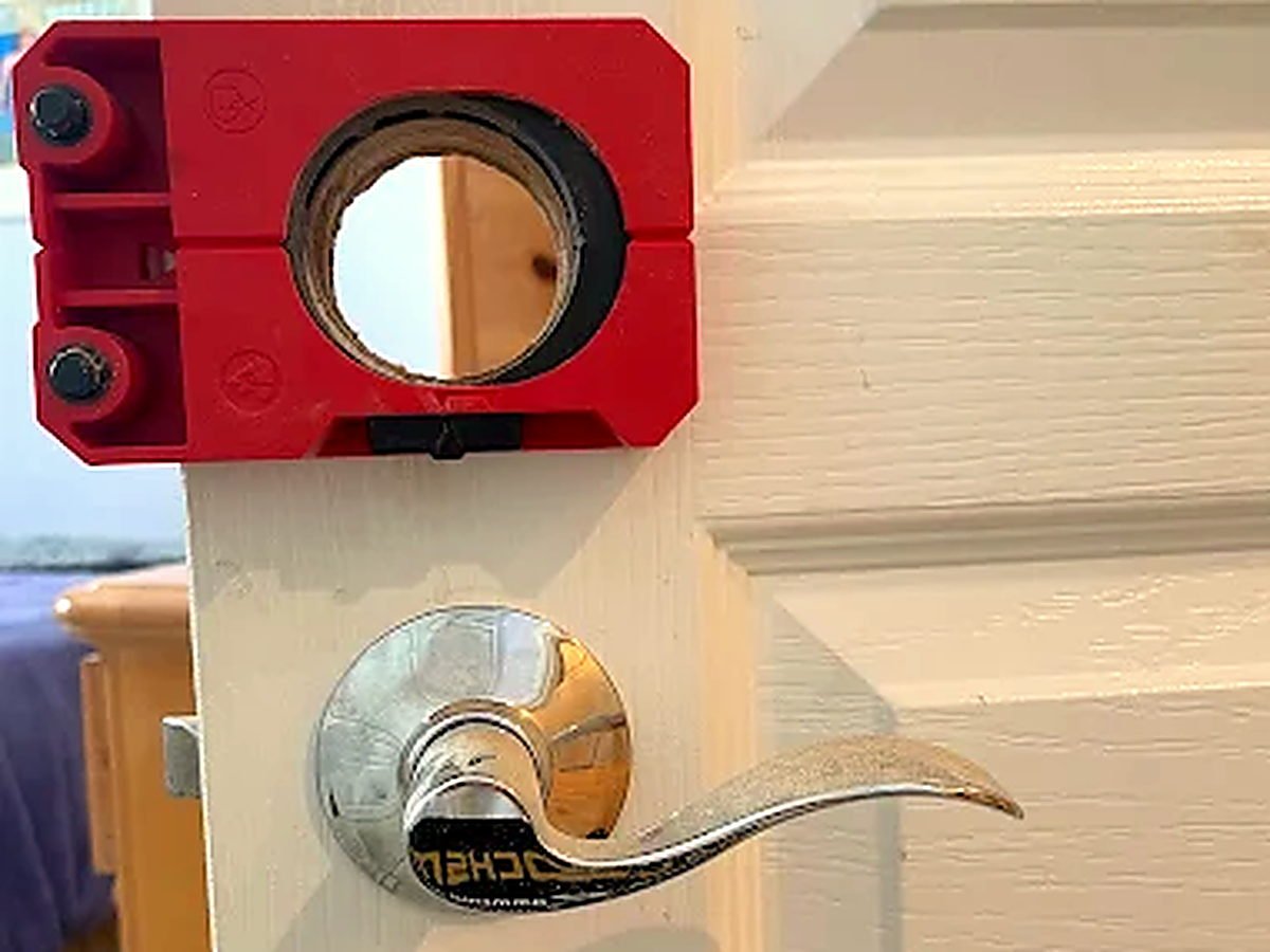 G.D. Locksmith fitting a new lock to the front door of a San Diego home, with the hole-saw jig clamped to the door