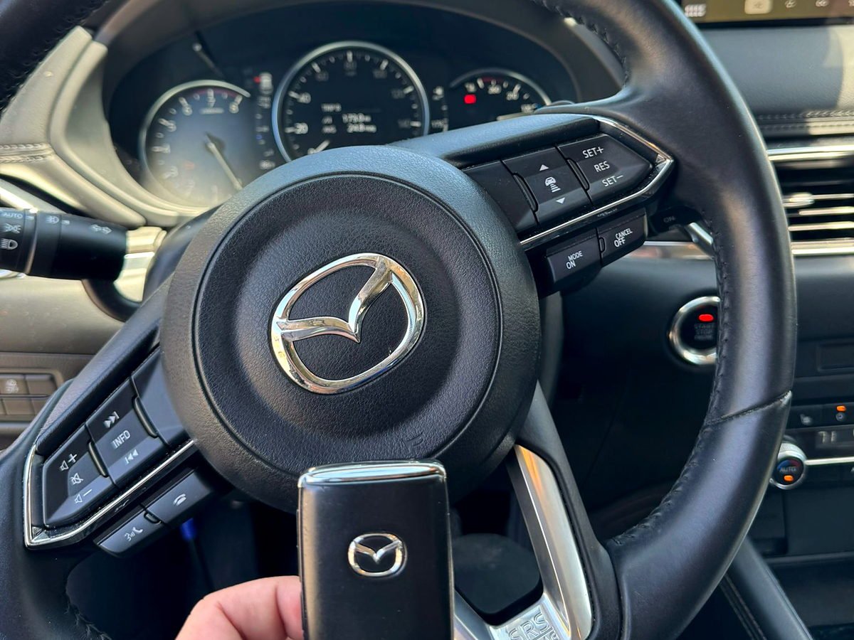 Replacement Mazda smart key held at the steering column and push-button ignition of the customer's car in San Diego
